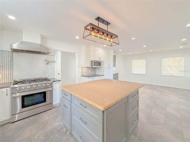 kitchen with premium range hood, decorative backsplash, a kitchen island, white cabinetry, and stainless steel appliances