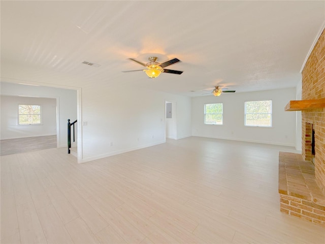 unfurnished living room featuring a fireplace, light wood-type flooring, and ceiling fan