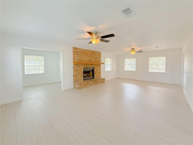 unfurnished living room featuring ceiling fan, light wood-type flooring, and a fireplace