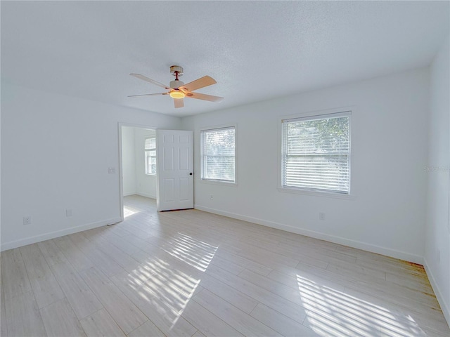 unfurnished room featuring ceiling fan, light hardwood / wood-style floors, and a textured ceiling