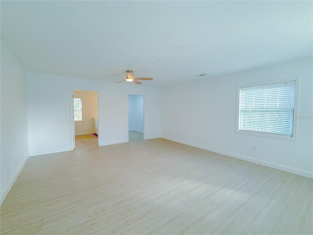 empty room with ceiling fan, light hardwood / wood-style flooring, a healthy amount of sunlight, and a textured ceiling