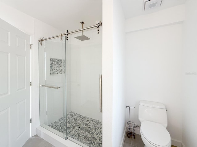 bathroom featuring tile patterned floors, toilet, and a shower with door