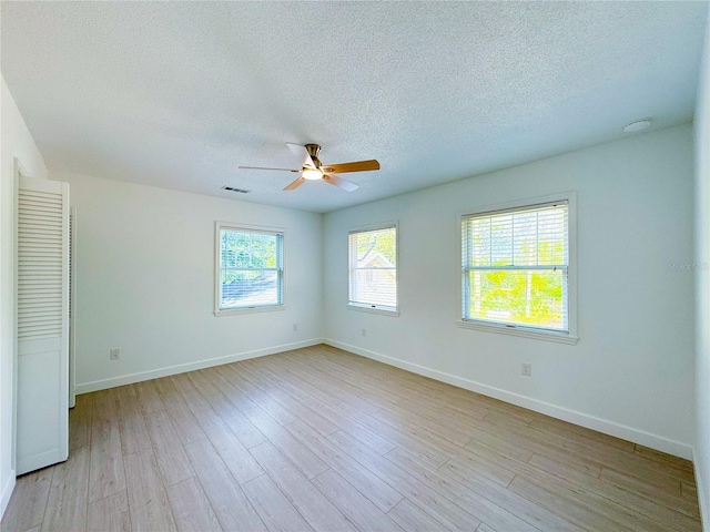 empty room featuring ceiling fan, a textured ceiling, and light hardwood / wood-style flooring