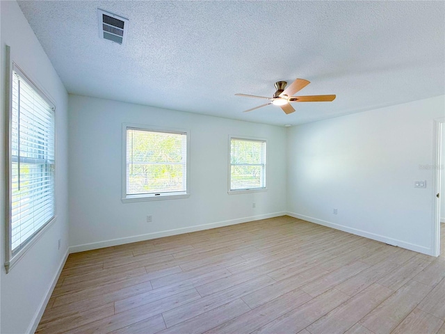 unfurnished room with ceiling fan, a textured ceiling, and light wood-type flooring