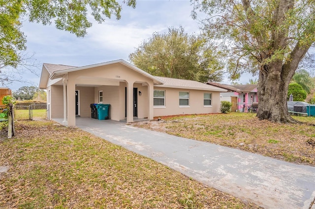 single story home featuring driveway, a gate, fence, a carport, and a front yard