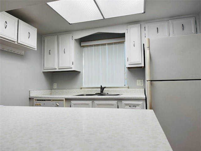 kitchen featuring sink, white cabinets, and stainless steel fridge