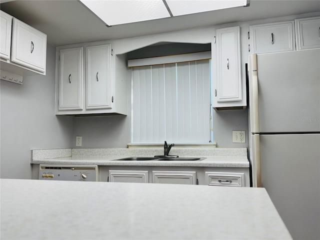 kitchen with sink, stainless steel fridge, dishwashing machine, and white cabinetry