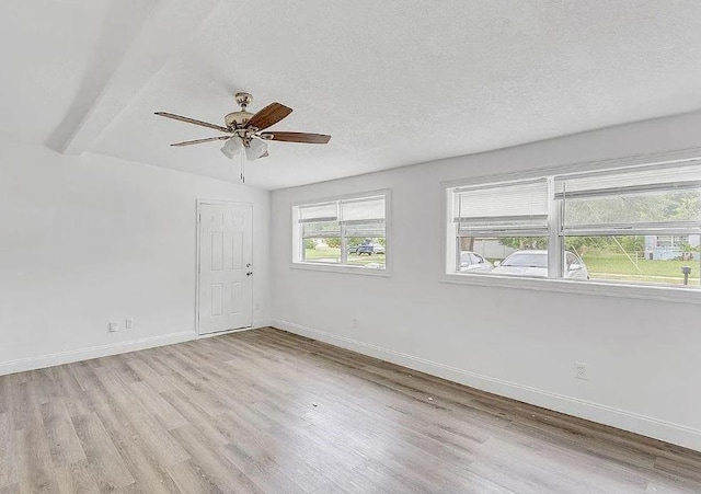 unfurnished room with light hardwood / wood-style floors, a textured ceiling, lofted ceiling with beams, and ceiling fan