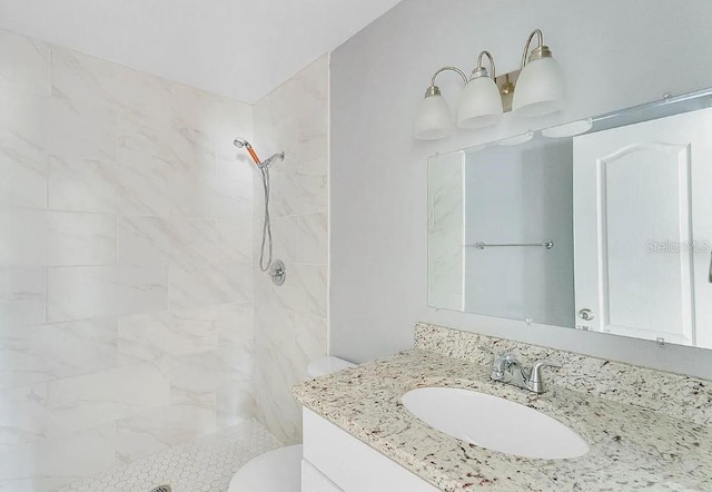 bathroom with tiled shower, toilet, and vanity