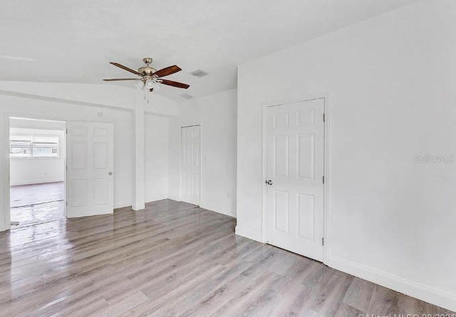 unfurnished room with ceiling fan, lofted ceiling, and light wood-type flooring