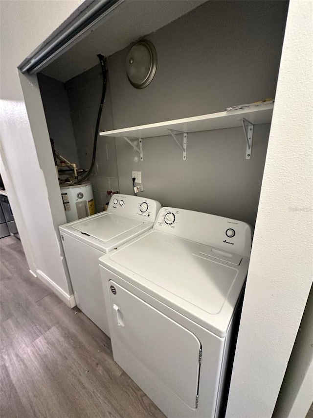 washroom featuring light wood-type flooring, washing machine and dryer, and electric water heater