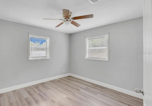 spare room featuring ceiling fan, light hardwood / wood-style flooring, and a textured ceiling