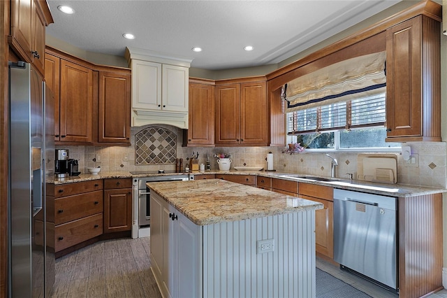 kitchen with light hardwood / wood-style floors, stainless steel appliances, a kitchen island, light stone counters, and sink