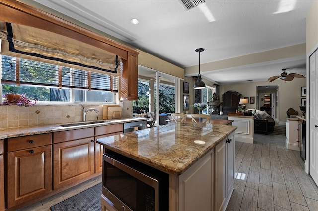 kitchen featuring ceiling fan, appliances with stainless steel finishes, decorative backsplash, a center island, and sink