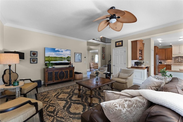 living room featuring ceiling fan, ornamental molding, and wood-type flooring