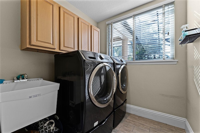 laundry room featuring sink, separate washer and dryer, a textured ceiling, and cabinets