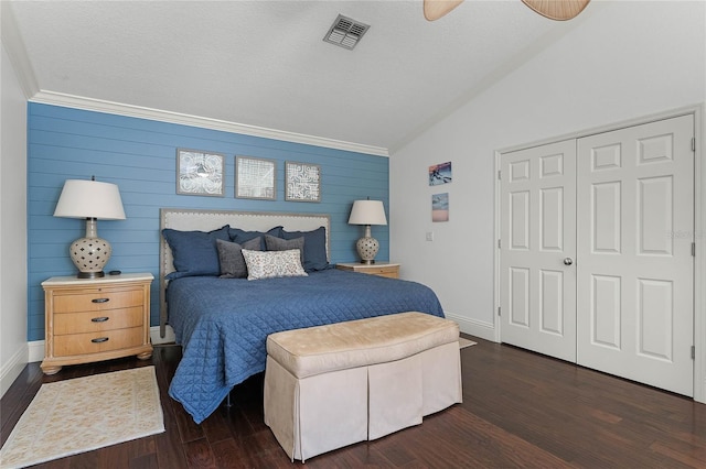 bedroom with dark wood-type flooring, a closet, wood walls, and vaulted ceiling