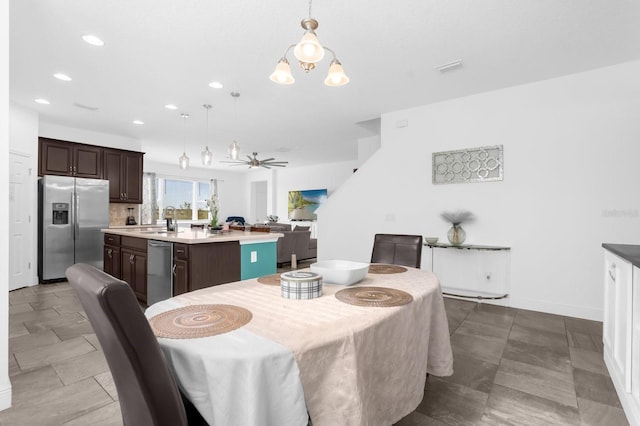 dining area with ceiling fan with notable chandelier and sink