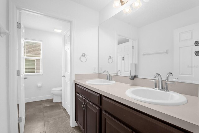 bathroom with toilet, vanity, and tile patterned flooring