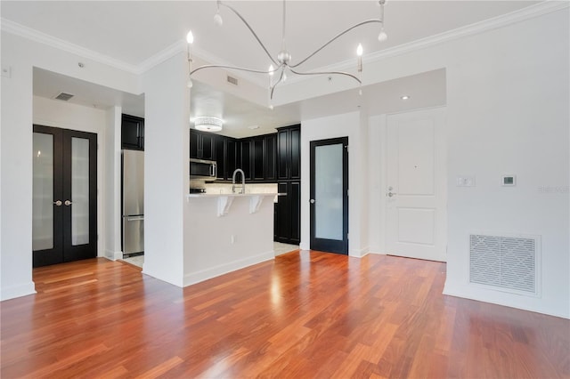 630 Vassar St Unit 2310, Orlando, FL 32804 - kitchen featuring french doors, a kitchen bar, crown molding, appliances with stainless steel finishes, and light hardwood / wood-style floors