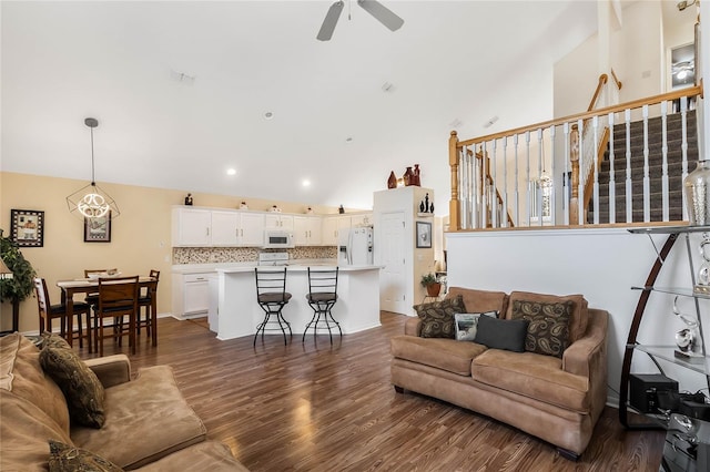 living room featuring ceiling fan, dark wood-type flooring, and lofted ceiling