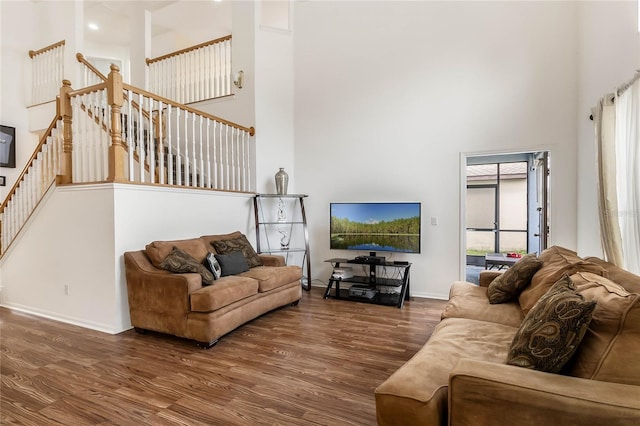 living room featuring a towering ceiling and dark hardwood / wood-style floors