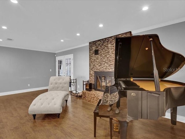 sitting room with ornamental molding, a stone fireplace, wood-type flooring, and french doors