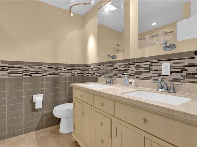 bathroom with a shower, tile walls, vanity, toilet, and tile patterned floors