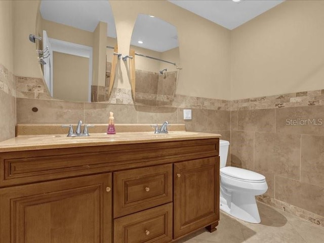 bathroom with walk in shower, tile patterned floors, toilet, tile walls, and vanity