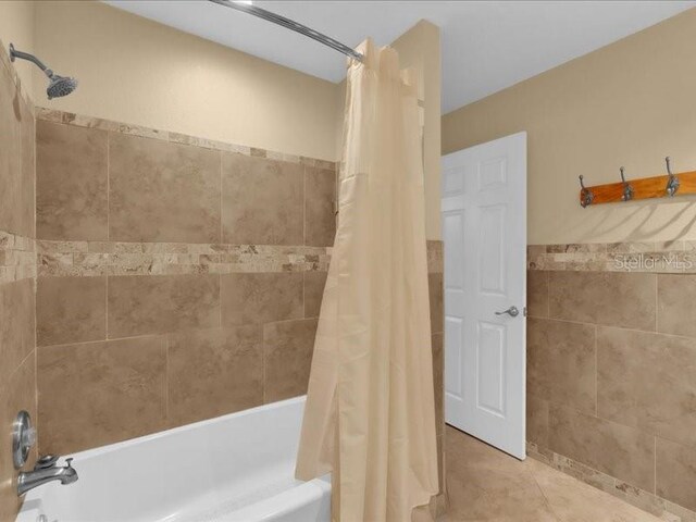 bathroom with tile walls, shower / tub combo, and tile patterned floors