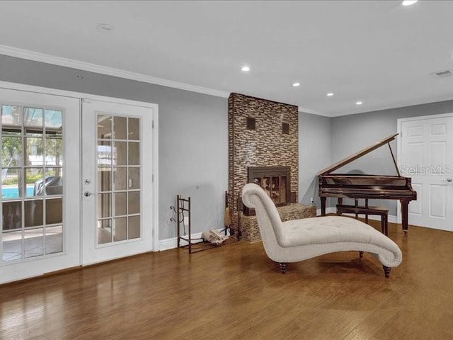 living area featuring french doors, a fireplace, dark wood-type flooring, and crown molding