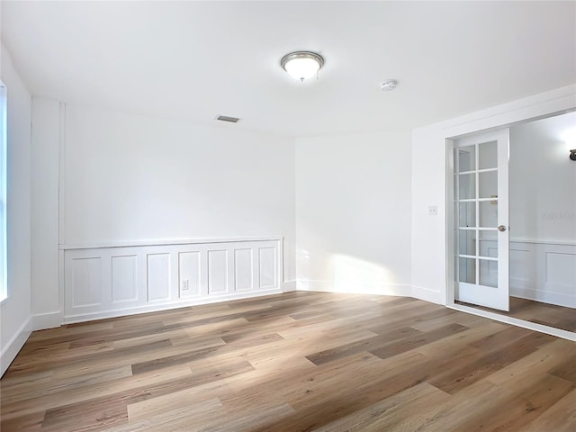 spare room featuring french doors and light hardwood / wood-style flooring