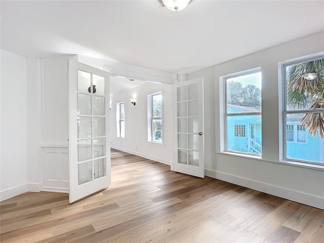 unfurnished room featuring french doors and light hardwood / wood-style flooring