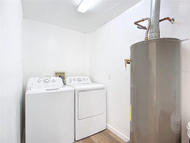 laundry room featuring washer and clothes dryer, light wood-type flooring, and water heater