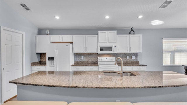 kitchen with sink, white appliances, white cabinets, and stone counters