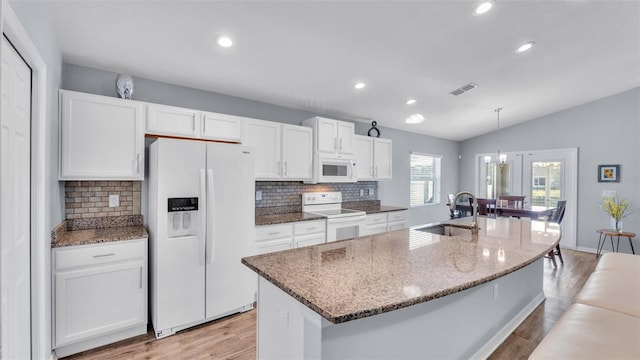 kitchen featuring lofted ceiling, a center island with sink, sink, white appliances, and white cabinets