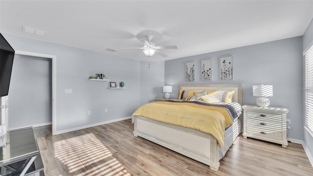 bedroom featuring ceiling fan, multiple windows, and light hardwood / wood-style flooring