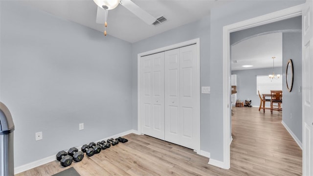 interior space featuring ceiling fan with notable chandelier and light hardwood / wood-style floors