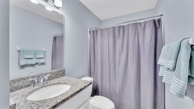 bathroom with curtained shower, toilet, and vanity