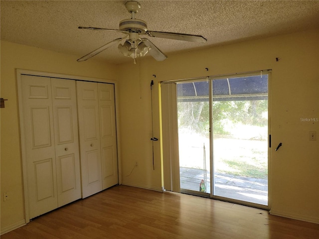 unfurnished bedroom featuring ceiling fan, access to exterior, a textured ceiling, and a closet