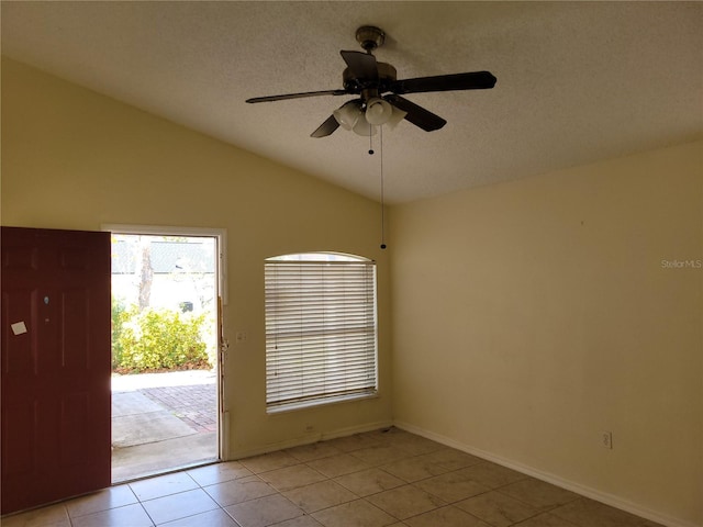 empty room featuring a textured ceiling, ceiling fan, light tile patterned floors, and lofted ceiling