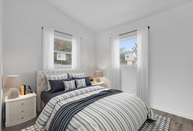 bedroom featuring multiple windows, dark hardwood / wood-style flooring, and lofted ceiling