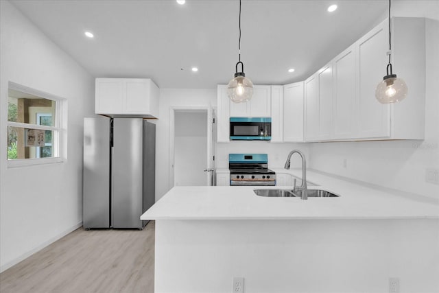 kitchen featuring sink, hanging light fixtures, stainless steel appliances, kitchen peninsula, and white cabinets