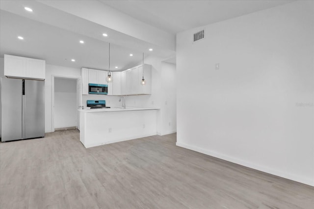 kitchen with sink, stainless steel fridge, stove, decorative light fixtures, and white cabinets