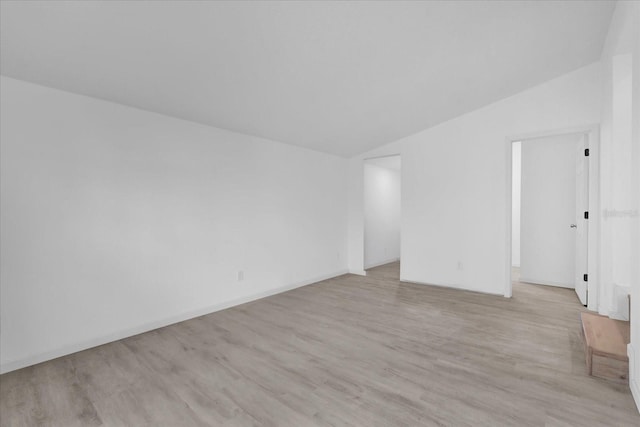 spare room with light hardwood / wood-style flooring and vaulted ceiling