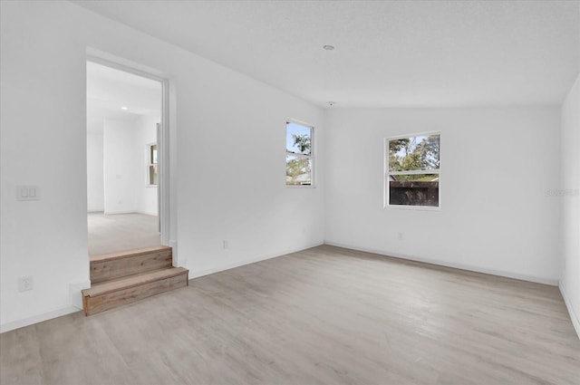 empty room with vaulted ceiling and light hardwood / wood-style flooring