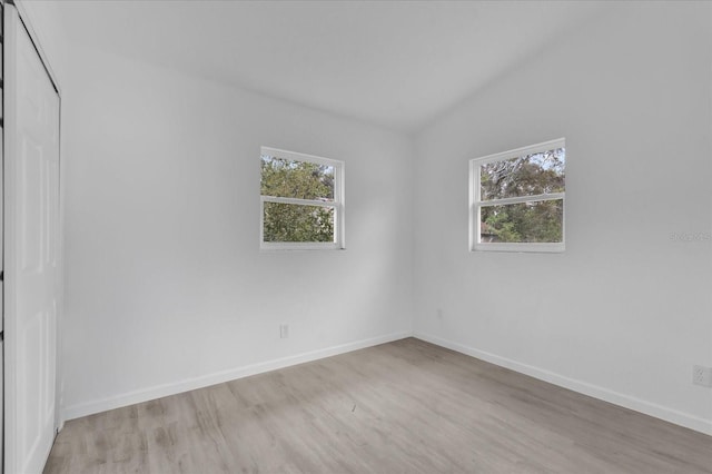 spare room with light hardwood / wood-style floors and lofted ceiling