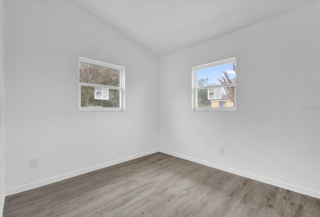 spare room with hardwood / wood-style floors and vaulted ceiling