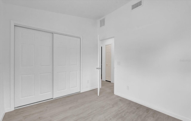 unfurnished bedroom with light wood-type flooring and a closet