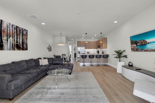 living room with light hardwood / wood-style flooring and sink